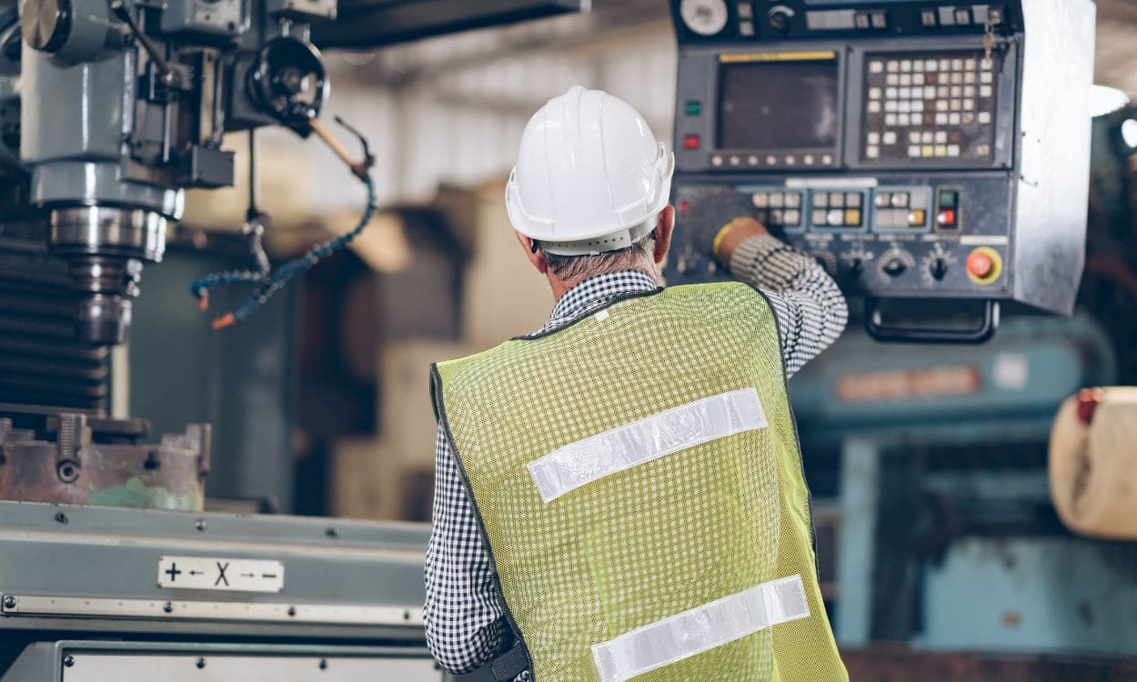 A man in a hard hat and vest operating machinery.