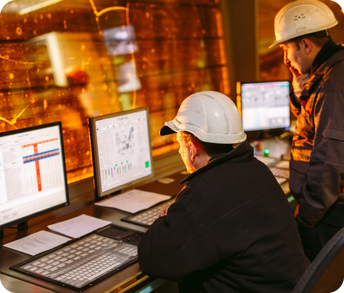 Two men in hard hats working on computers.